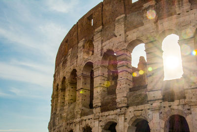 Low angle view of coliseum against sky on sunny day