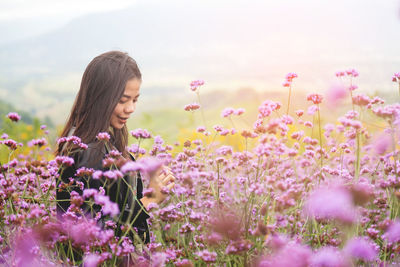 Woman standing by pink flowering plants