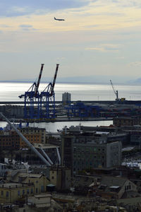 Cranes at harbor against sky