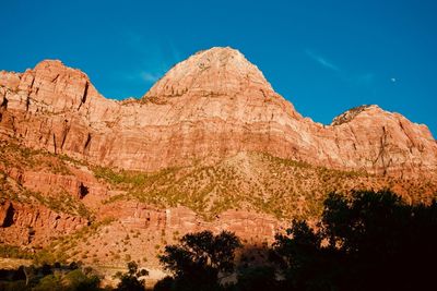 Low angle view of majestic rocky mountains against blue sky