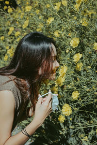 Side view of young woman looking at sunflower field