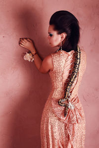 Woman standing against pink wall