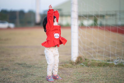 Full length of girl standing by soccer goal at field