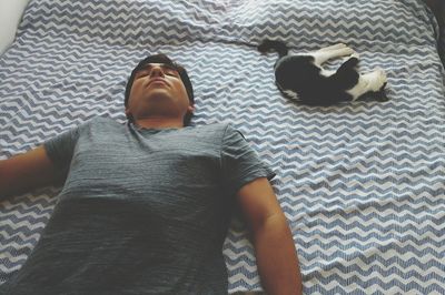 Man sleeping with cat on bed at home