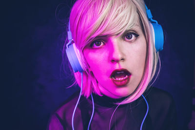 Close-up portrait of beautiful woman wearing headphones against black background