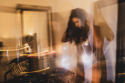 Blurred motion of young woman playing music at home