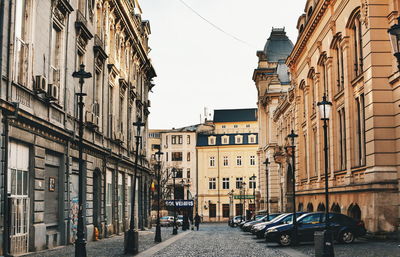 Vehicles parked on roadside amidst buildings in city