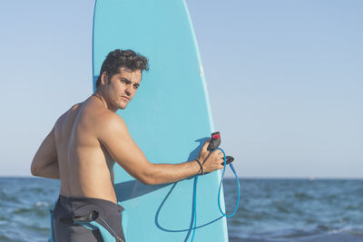 Full length of shirtless man holding sea against sky