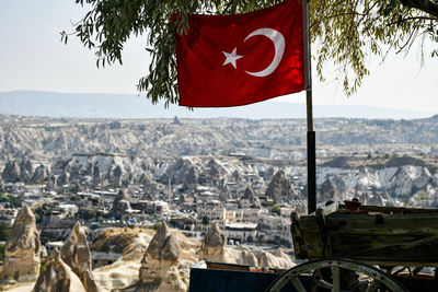 Red flag by buildings against sky in city