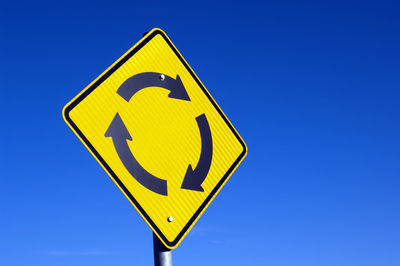 Low angle view of road sign against blue sky