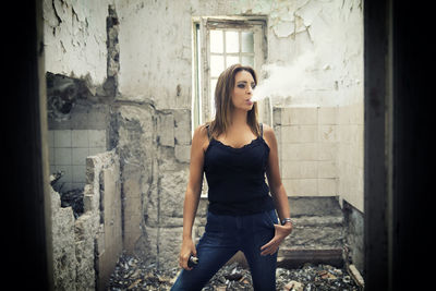 Portrait of young woman standing against wall