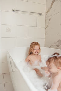 Little brother and sister bathing in a foam bath