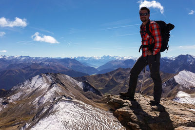 Full length portrait of young man hiking on alps against sky during winter