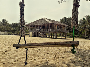 Lifeguard hut on sand against trees against sky