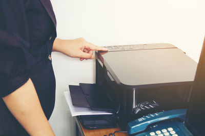 Midsection of woman working on equipment in office