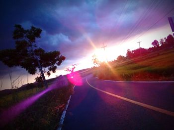 Road amidst trees against sky during sunset