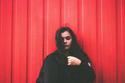 Portrait of woman standing against red wall