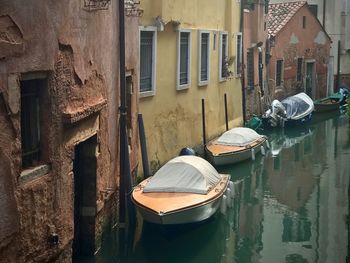 Boats moored on canal by buildings in city