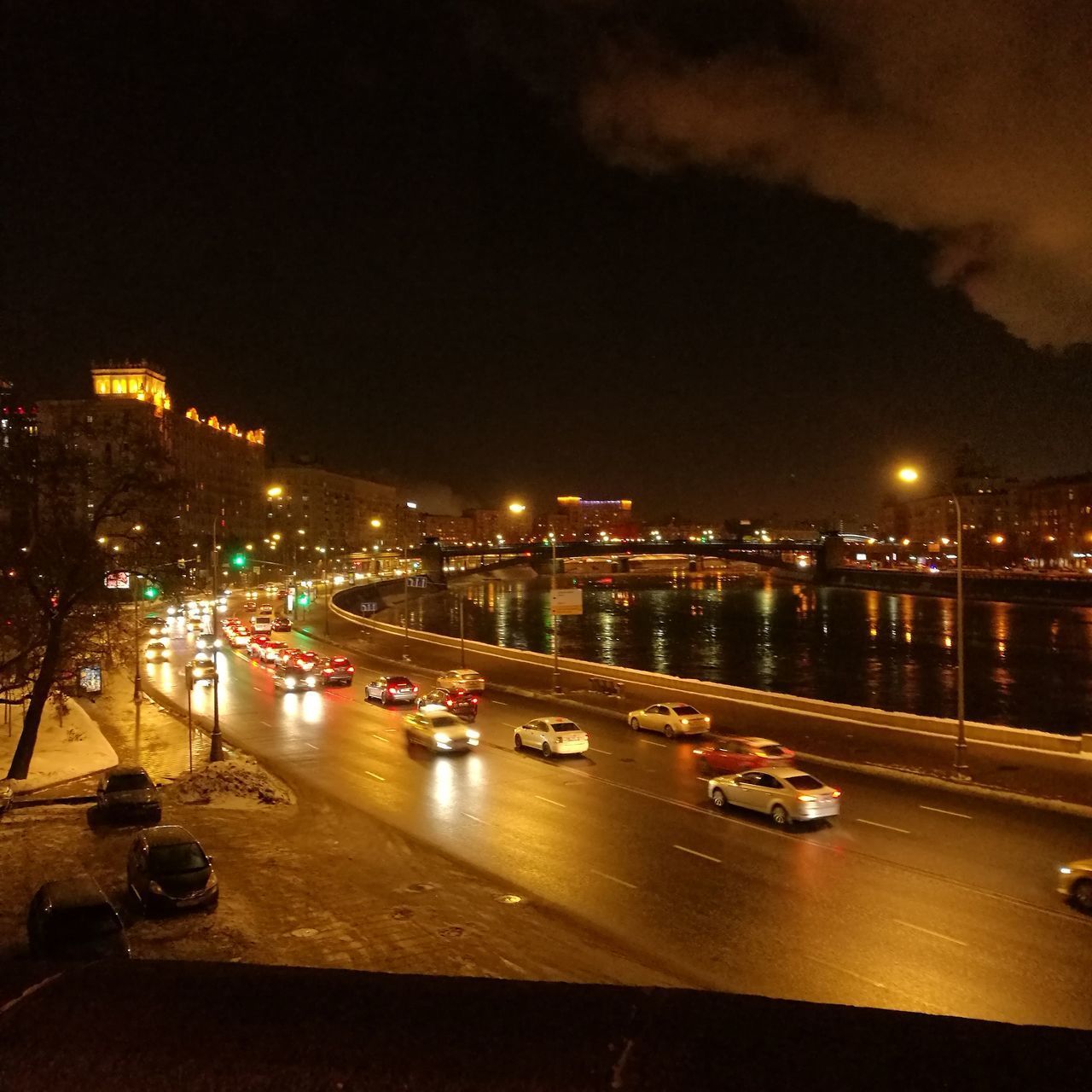 CARS ON ILLUMINATED CITY STREET AGAINST SKY