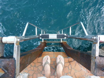 Low section of man standing by ladder in boat over sea