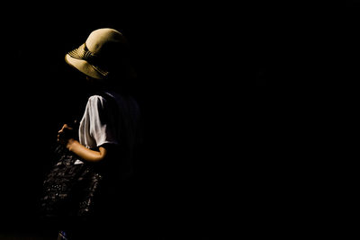 Side view of woman standing against black background