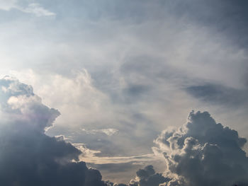 Low angle view of sunlight streaming through clouds