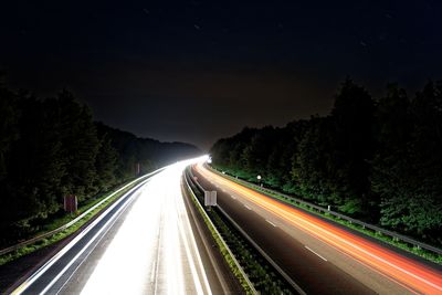 Light trails on road against sky at night