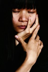 Close-up of young woman with eyes closed napping against black background