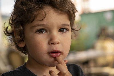 Close-up portrait of cute boy licking fingers