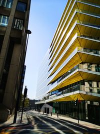 Street amidst buildings against clear blue sky