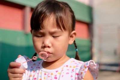 Close-up of cute girl holding bubble wand outdoors