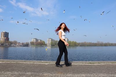 Full length of young woman flying birds