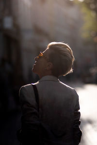 Rear view of woman looking away while standing outdoors