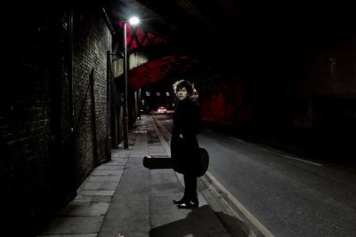 Woman walking on illuminated street at night