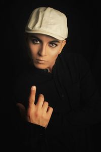 Portrait of woman wearing hat against black background