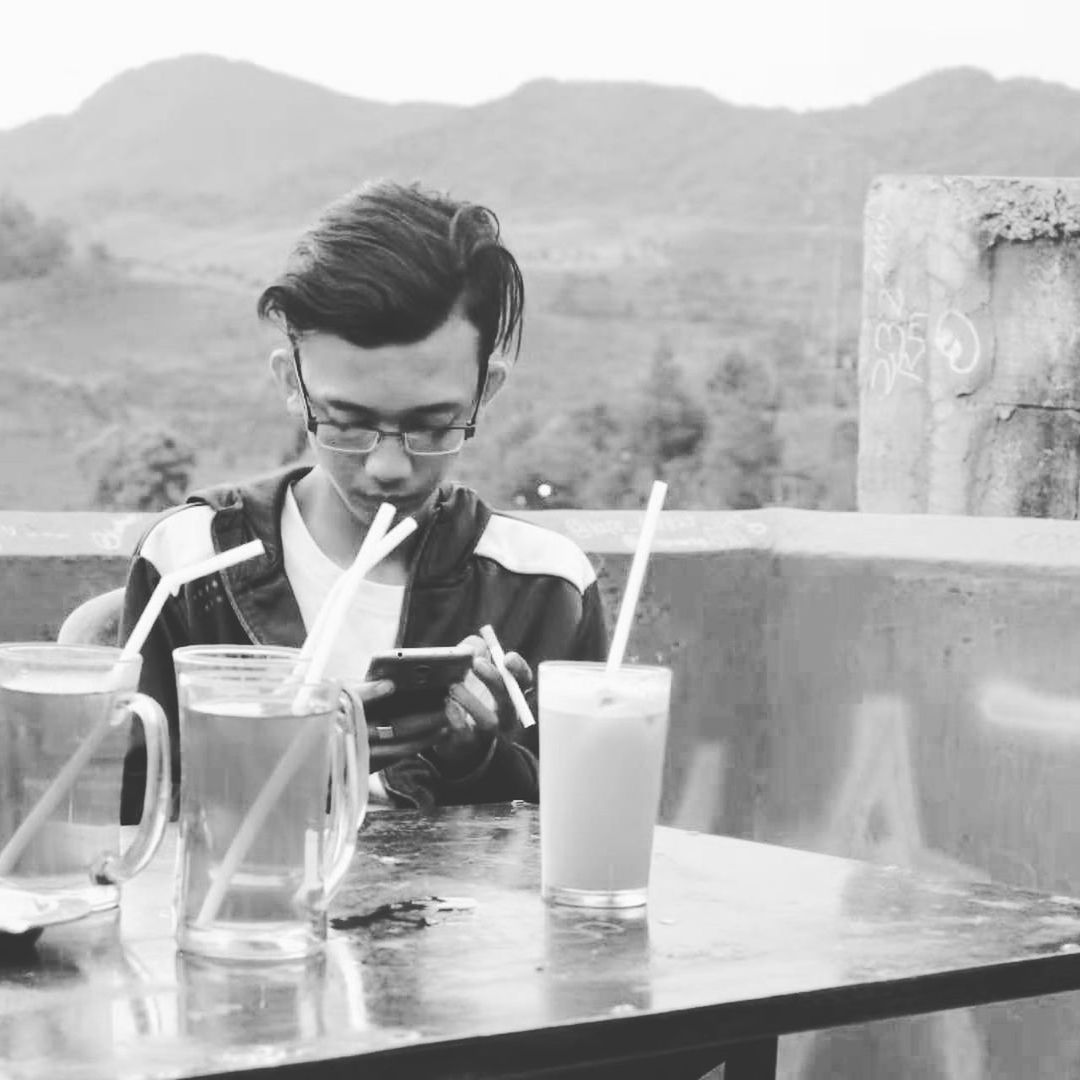 drink, one person, food and drink, table, refreshment, drinking glass, adult, black and white, men, glass, mountain, monochrome photography, white, glasses, monochrome, water, household equipment, sitting, nature, young adult, business, lifestyles, food, portrait, outdoors, activity, drinking, eyeglasses, front view, soft drink, looking down, day, leisure activity, relaxation