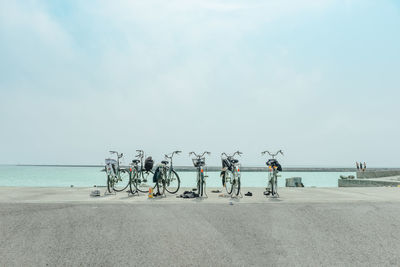 Bicycles parked in front of sea against sky