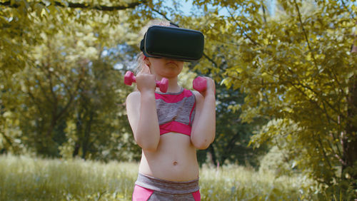 Rear view of young woman standing against trees