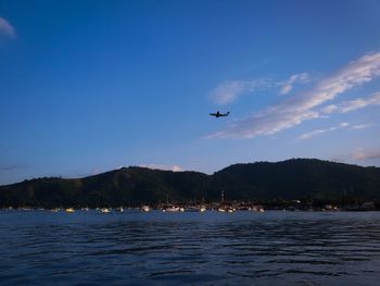 Boats in sea with mountain in background