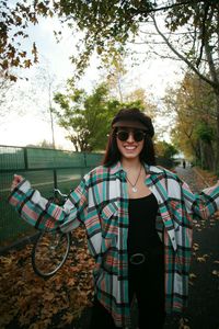 Portrait of smiling young woman standing against trees