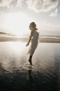 Woman jumping over sea against sky