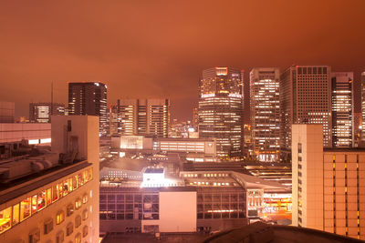 Illuminated buildings in city against sky at night