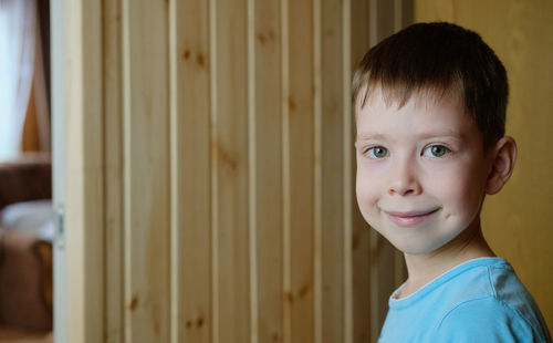 Portrait of a smiling boy, on a wooden background, copy space. cute boy of european appearance,