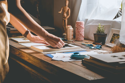 Midsection of woman holding paper at table