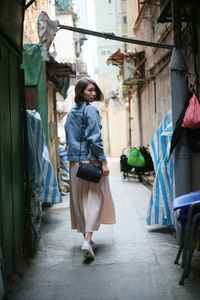 Rear view portrait of young woman walking in alley