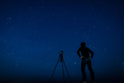 Silhouette man photographing against sky at night