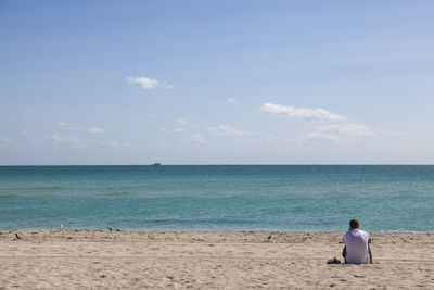 Rear view of man on beach against sky