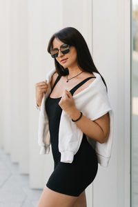 Young woman in a black sporty outfit with a white sweatshirt draped over her shoulders