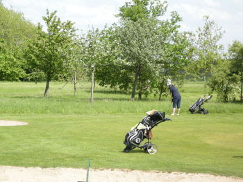 Woman playing while standing by golf bag at course