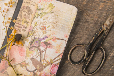 Directly above shot of old scissors with book and wilted flower on wooden table